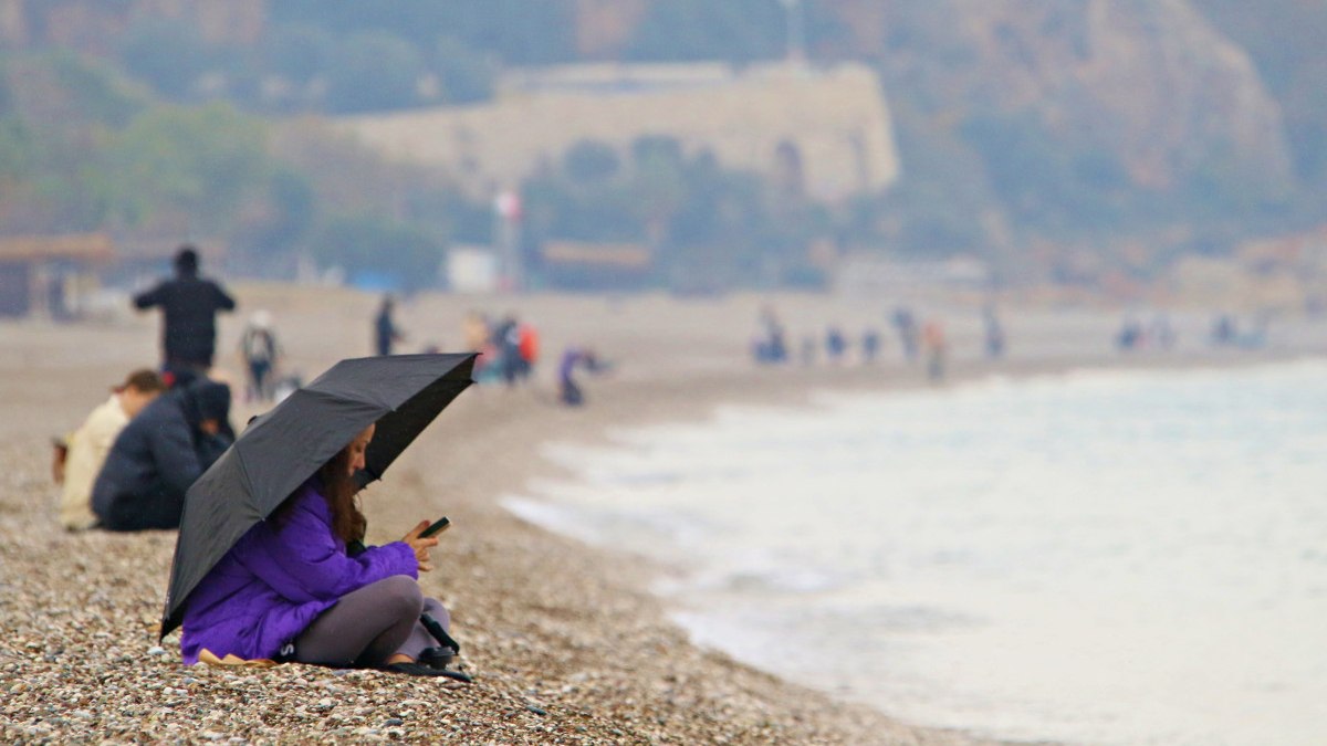 Antalya’da yağmura rağmen şemsiye altında deniz keyfi